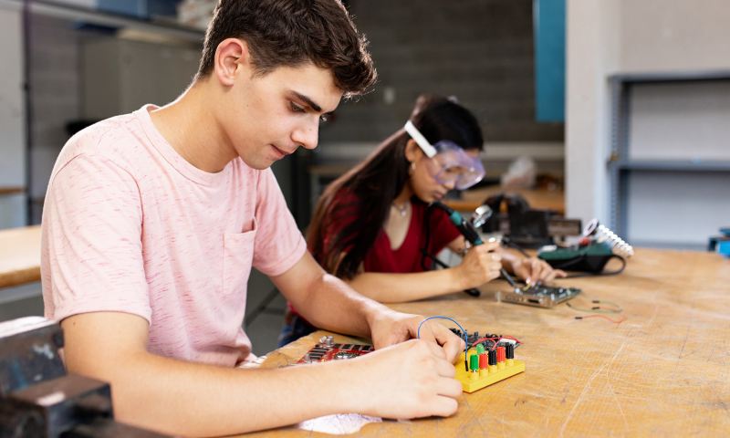 Diverse young high school students learning in science robotics electronic class